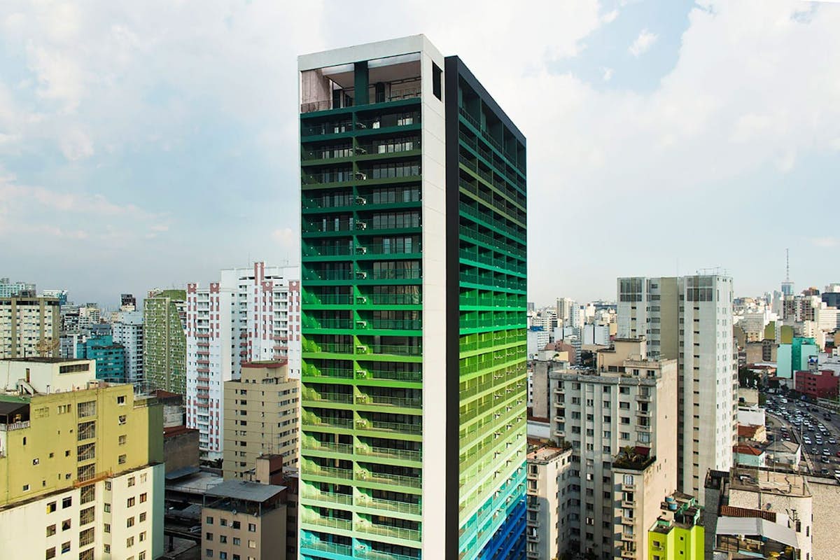 Fachada colorida de edifício com pintura degradê em tons de azul e verde.
